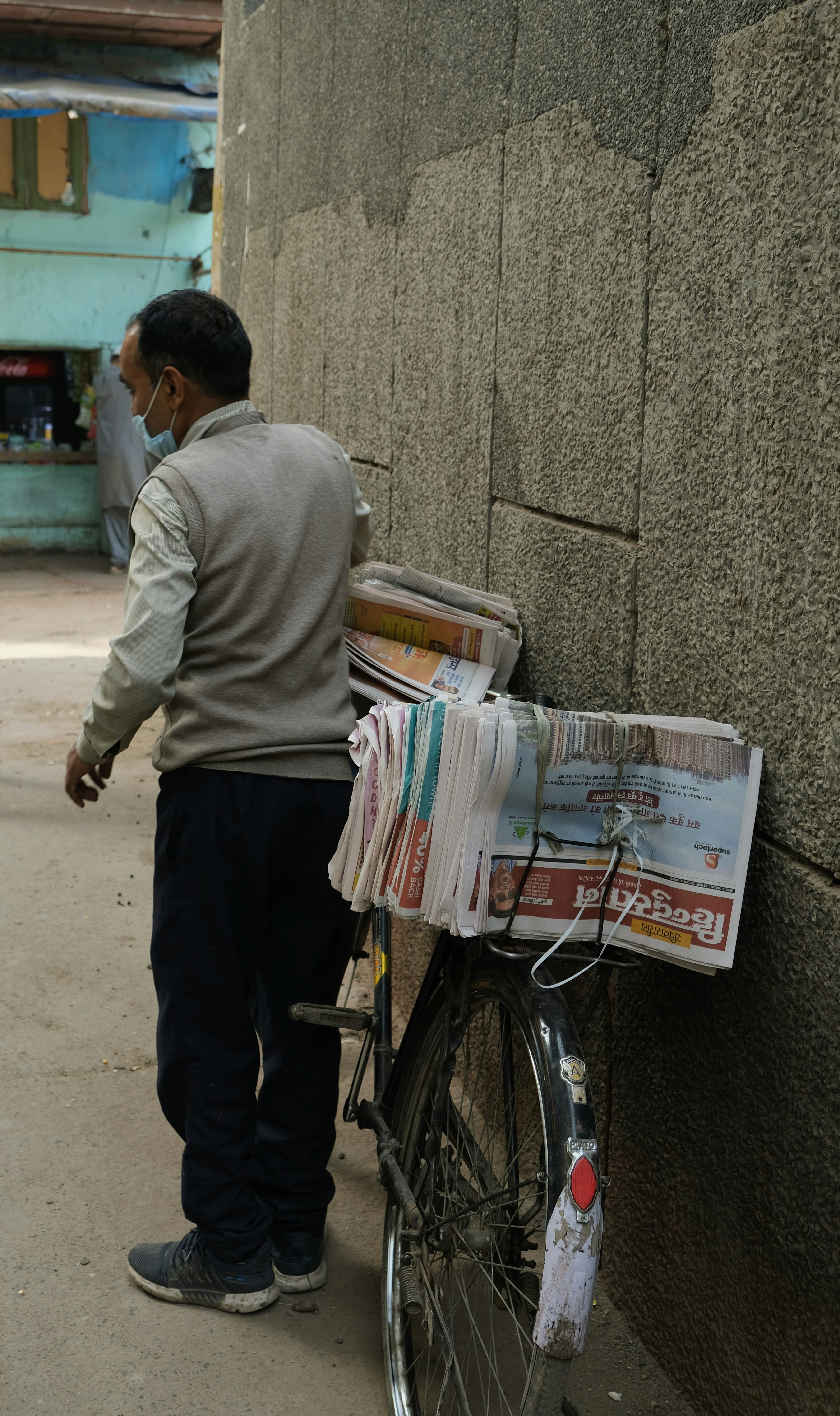 man in gray sweater and black pants standing beside bicycle